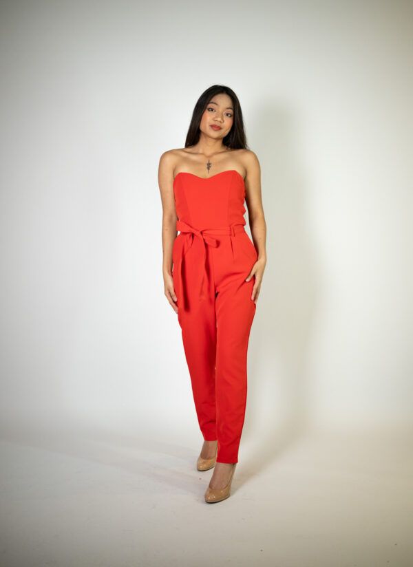 Alt text: "Red strapless jumpsuit called Plume, featuring a tie belt, perfect for glamorous occasions."