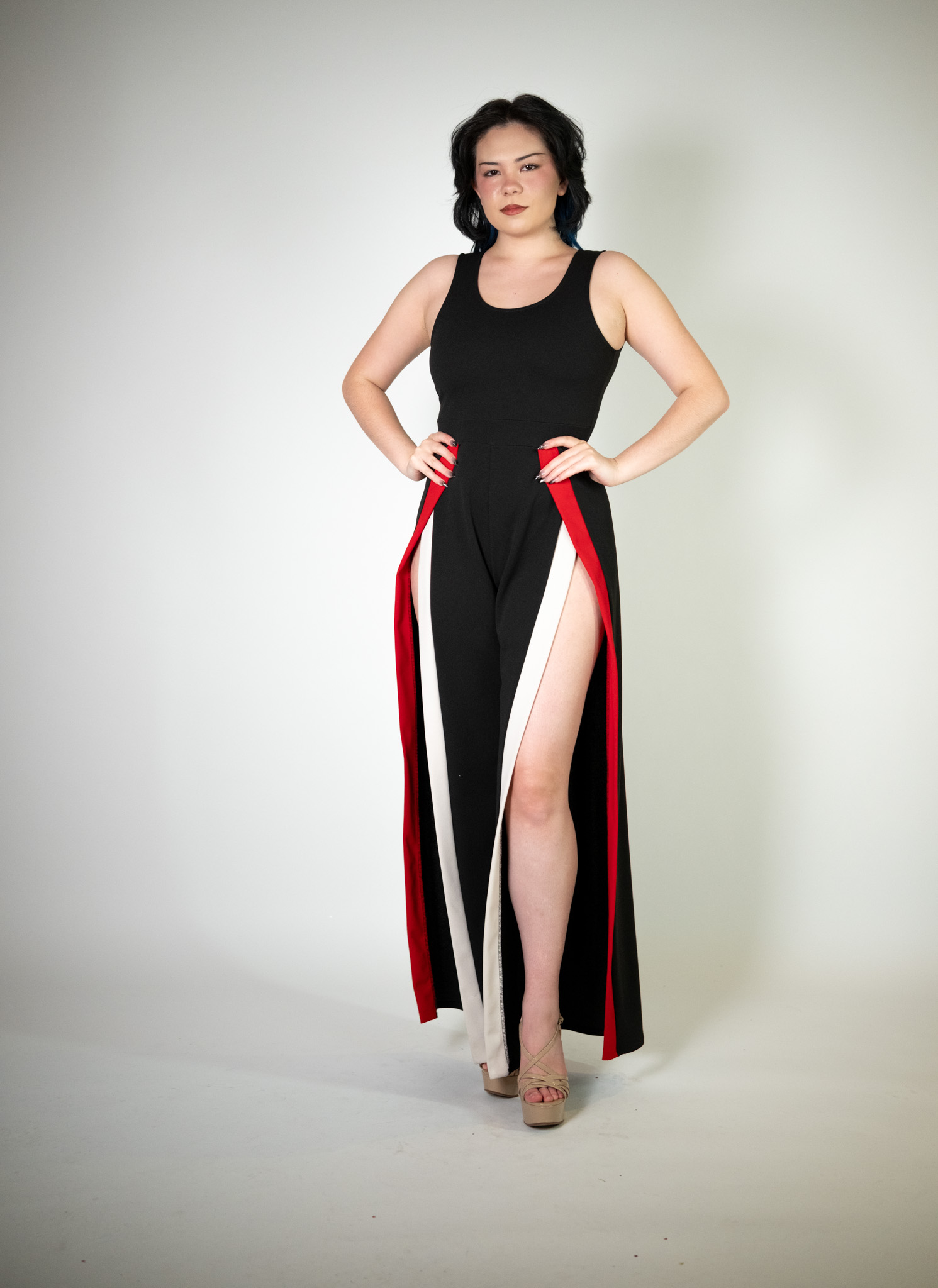 Alt text: "Black jumpsuit called Zoura, featuring white and red hem details and two high slits, perfect for glamorous occasions."