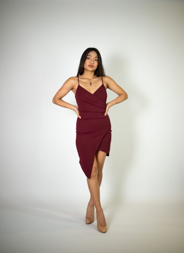 Alt text: "Red-purple mauve mini dress called Ines, featuring a wrap V-neck, angled slit, and ruching details, perfect for special occasions."