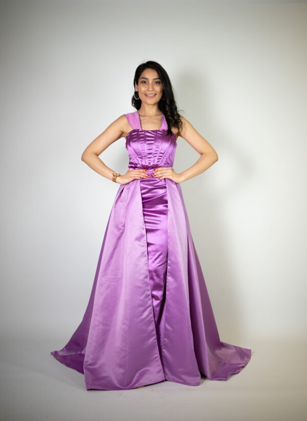 Alt text: "Purple satin gown called Kaja, featuring thick straps and a removable overskirt, perfect for special occasions."