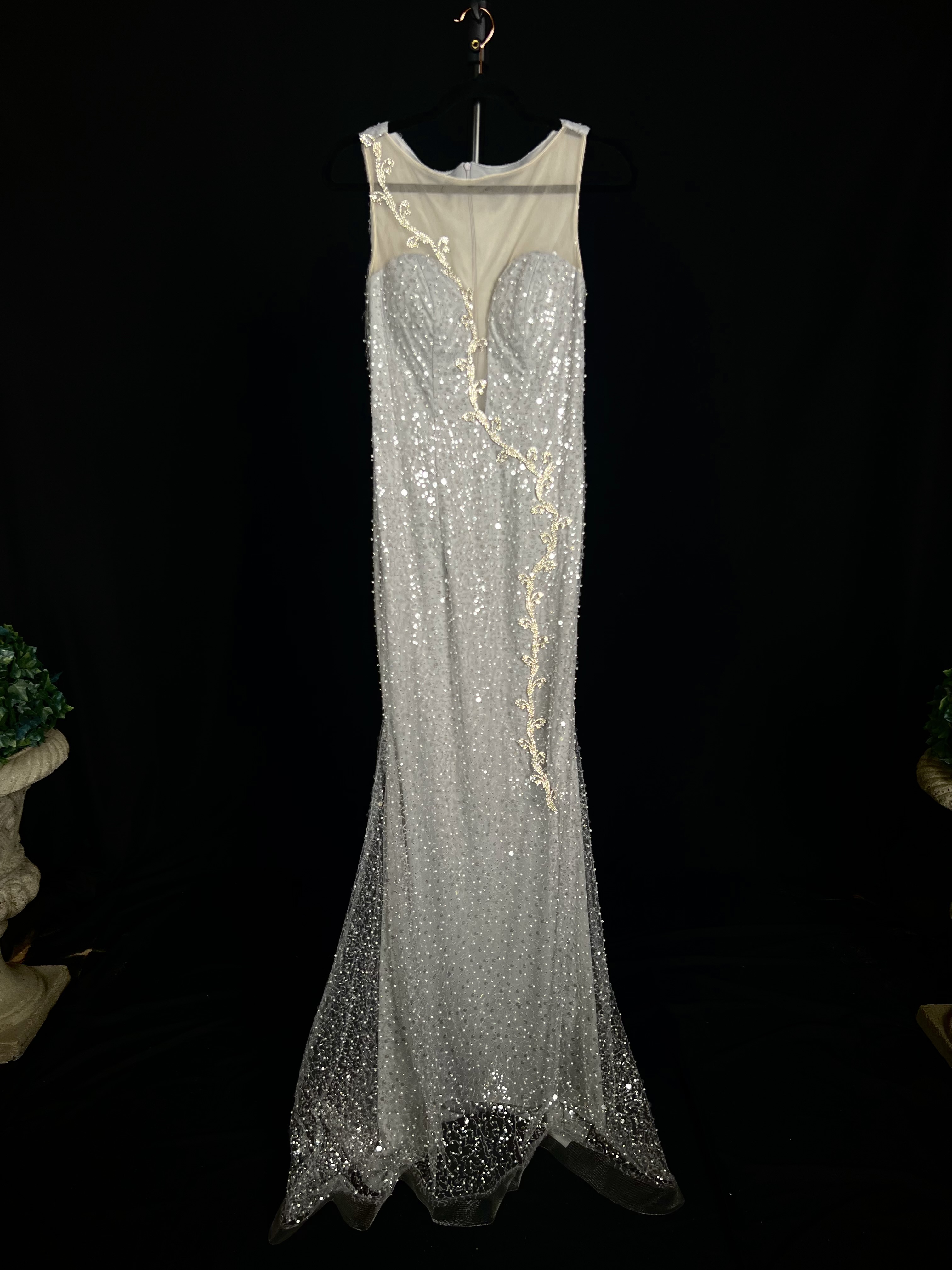 Alt text: "Silver evening gown called Freesia, featuring an illusion neckline, 3D silver details, and a chapel-length train, perfect for formal occasions."