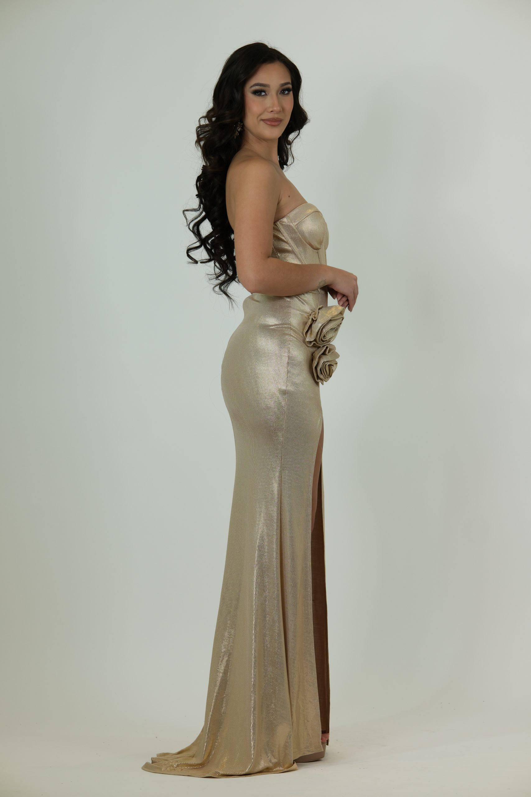 "Gold strapless evening gown called Amaris, featuring a corset-style bodice, high slit, floral hip detail, and floor-length skirt."