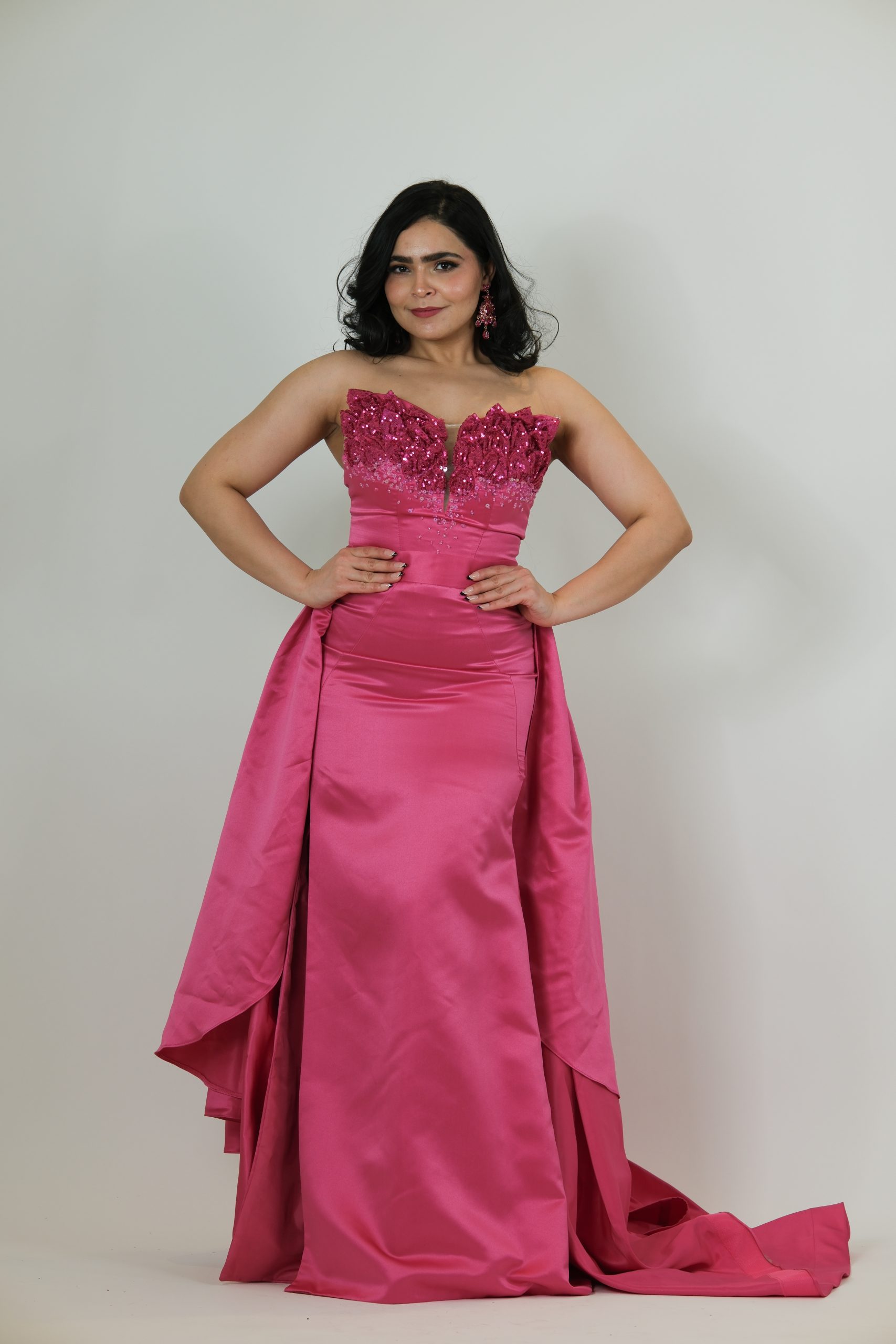 “Fuchsia strapless gown with beaded sweetheart bodice and satin skirt with a dramatic detachable overskirt.”