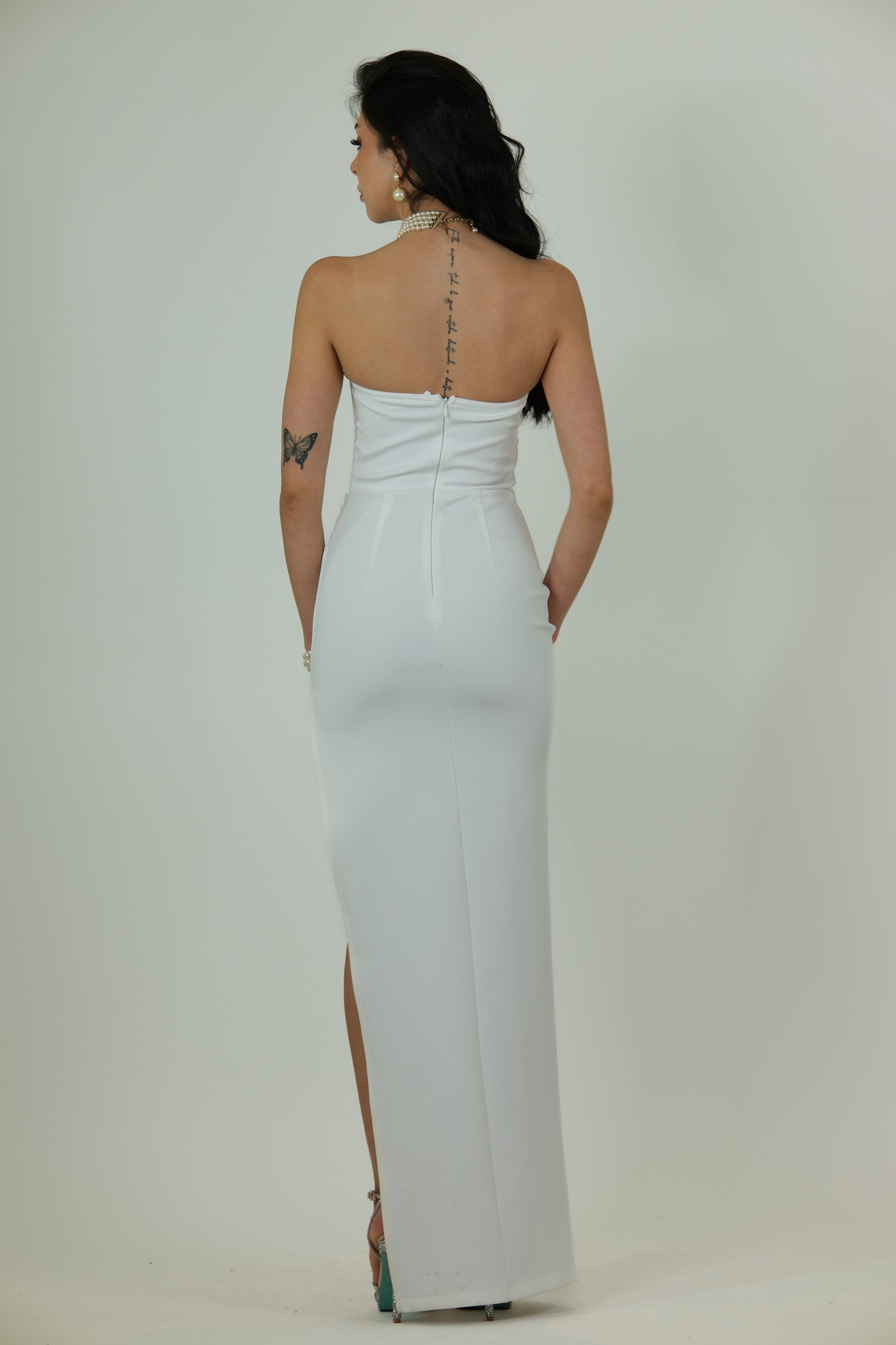 White strapless gown with structured bustier, sheer boning details, and a high thigh slit.