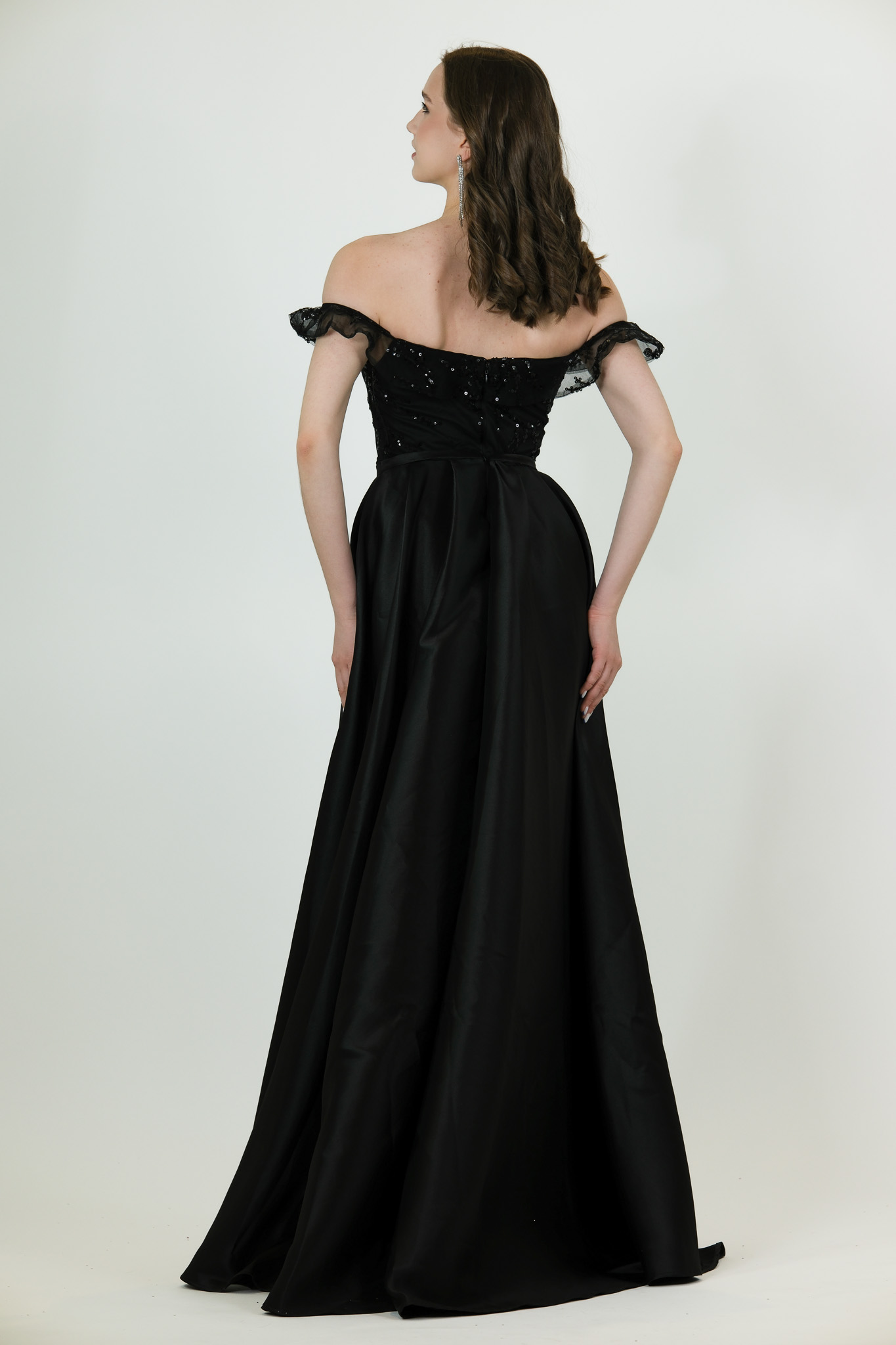 “Black off-shoulder beaded gown with attached overskirt and fitted silhouette.”