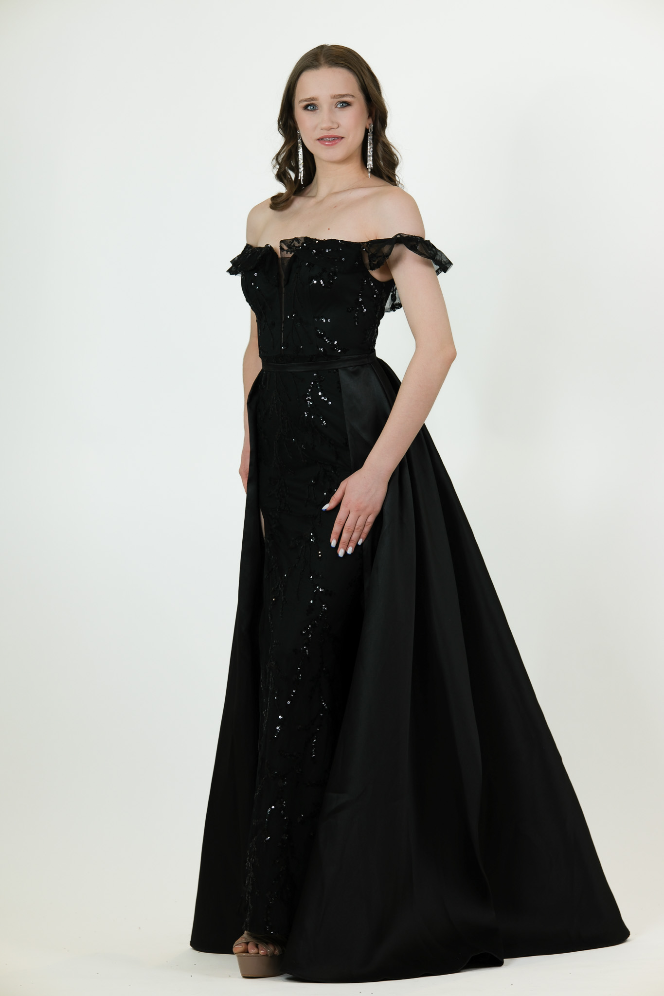 “Black off-shoulder beaded gown with attached overskirt and fitted silhouette.”