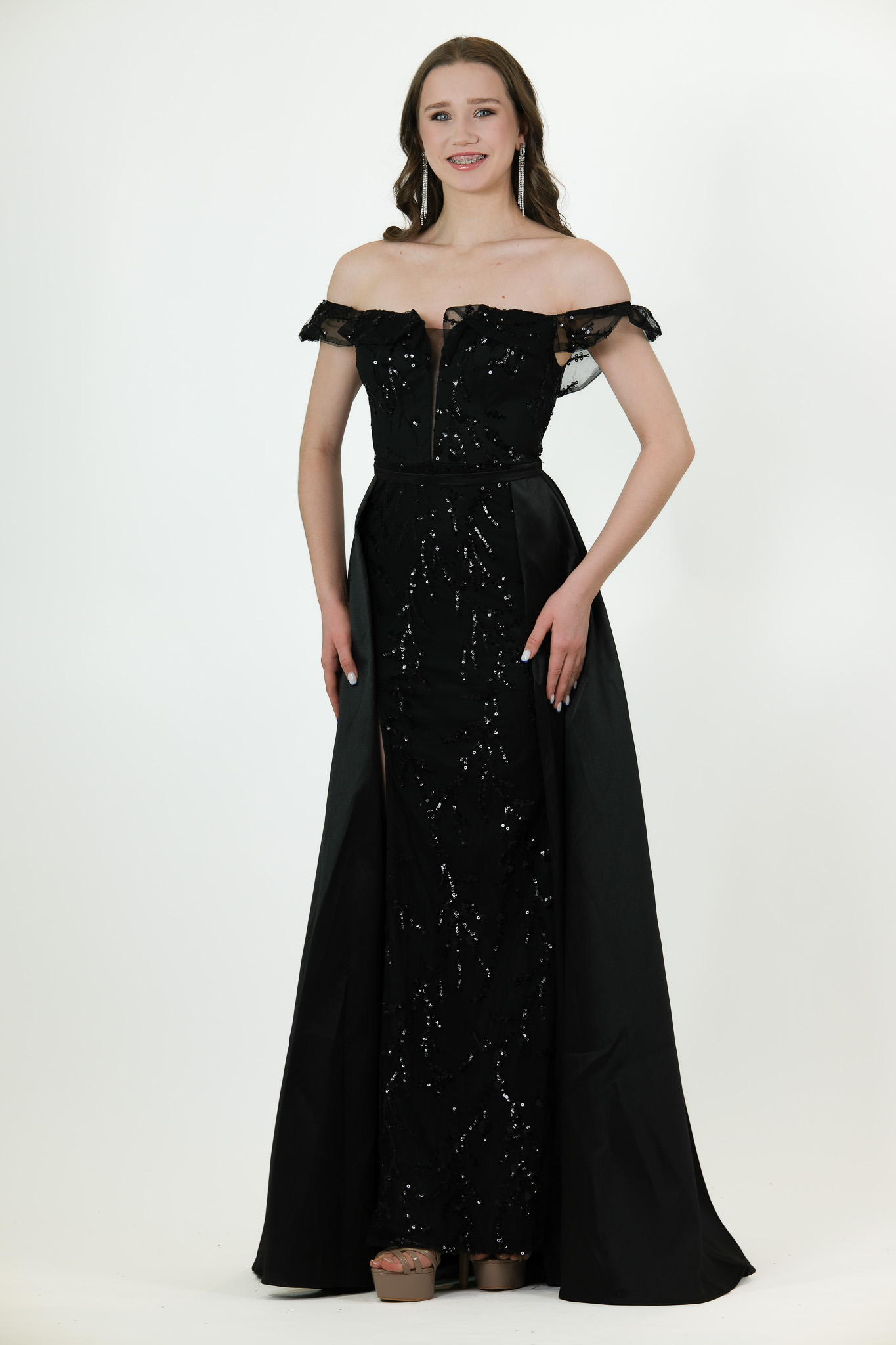 “Black off-shoulder beaded gown with attached overskirt and fitted silhouette.”