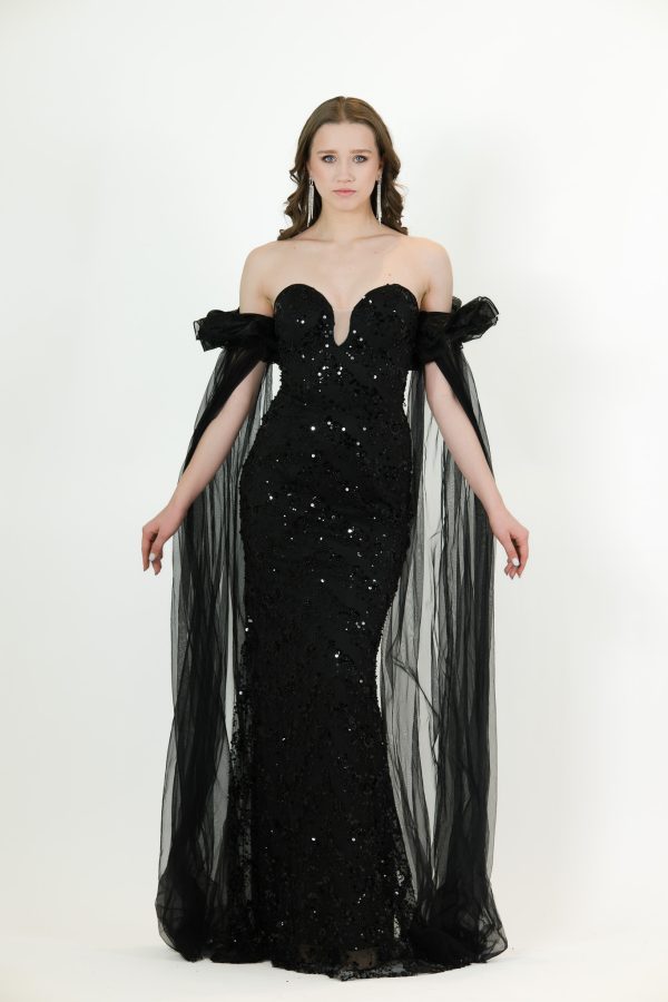 “Black sequin gown with sweetheart neckline and long draped off-shoulder tulle sleeves.”