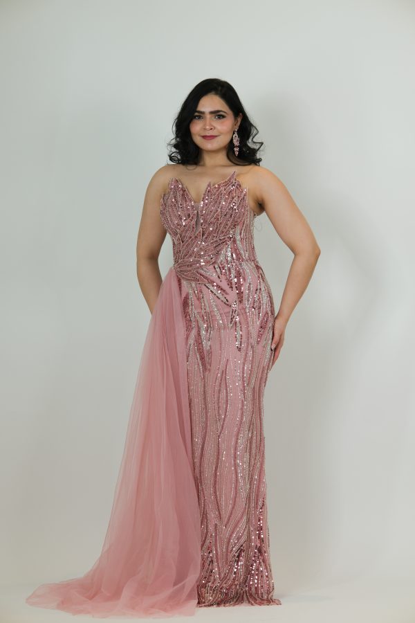 “Blush pink sequin gown with fitted silhouette and soft tulle side drape.”