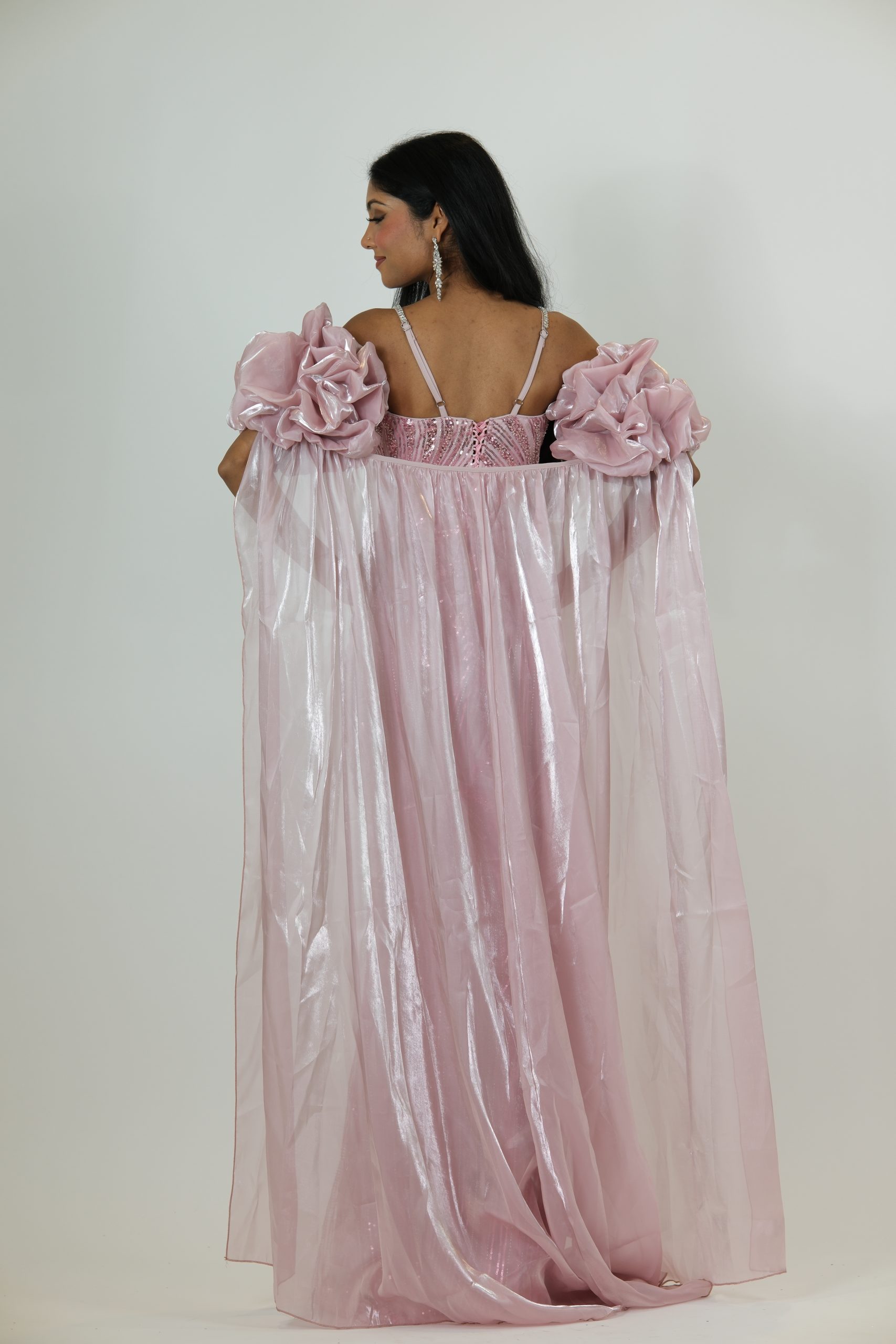 “Blush pink sequin gown with diamond straps, dramatic puff sleeves, and a long glossy cape.”