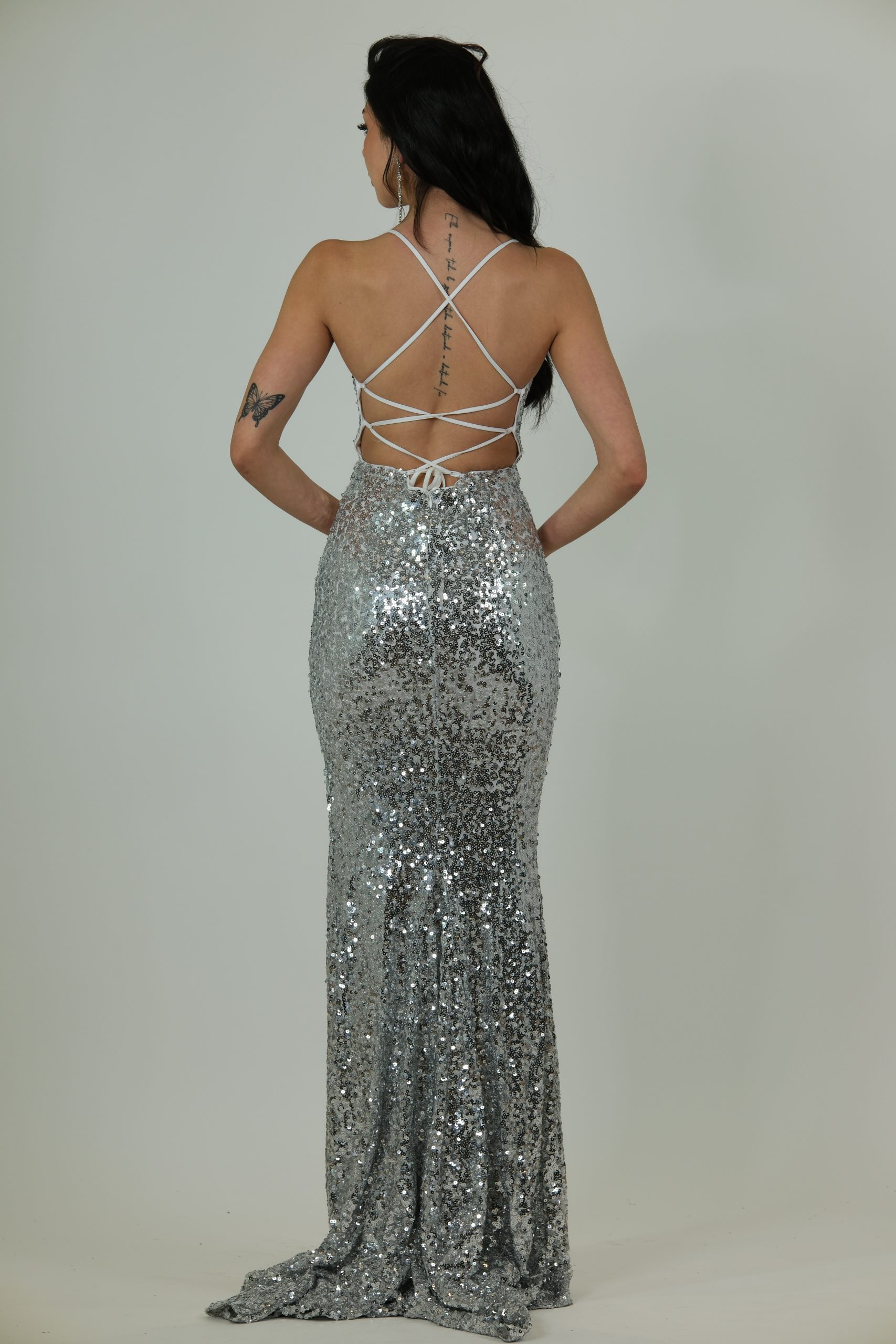 "Silver sequin gown with thin straps, V-neckline, and a high thigh slit."