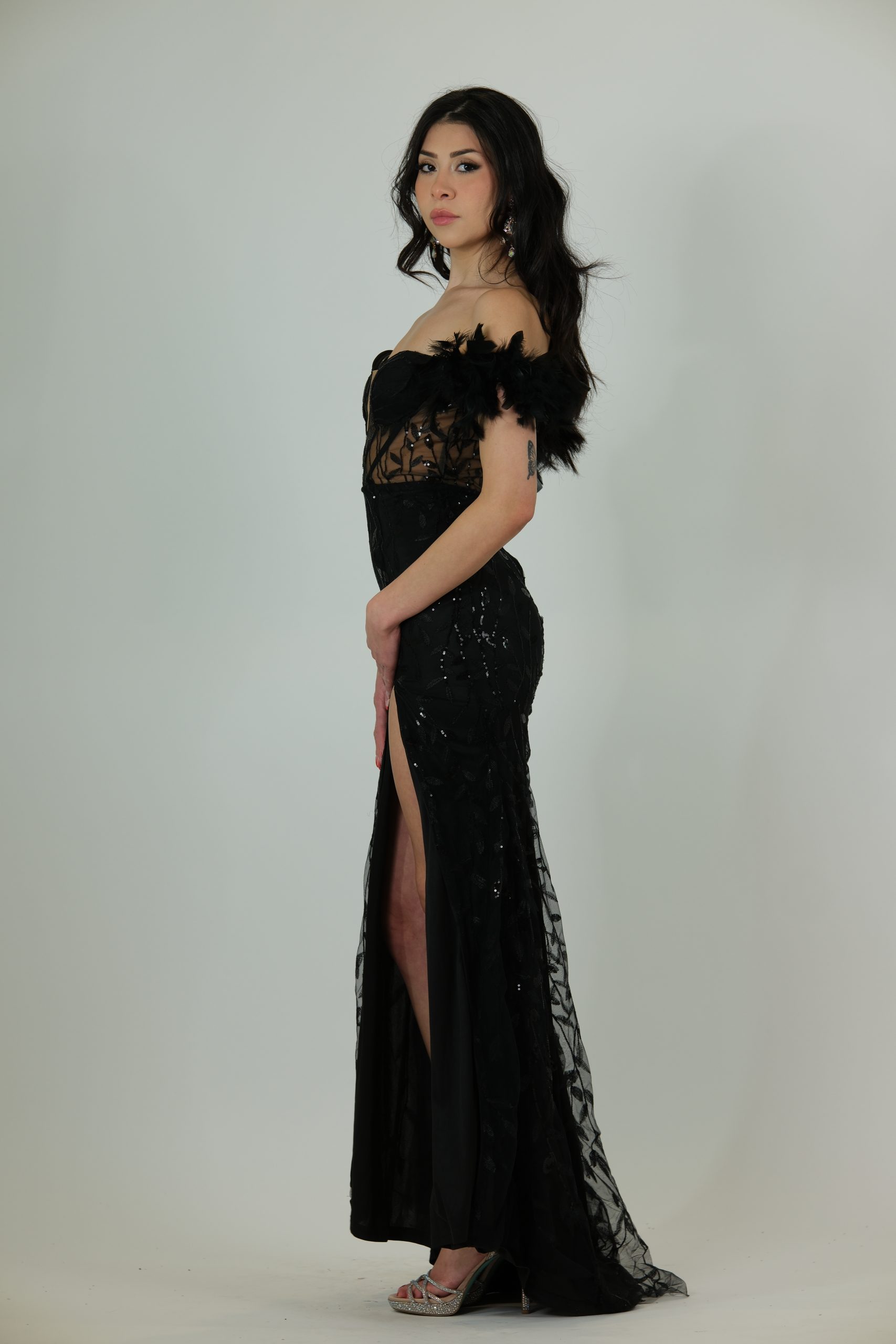 "Black sheer corset gown with feathered off-shoulder sleeves, sequin detailing, and a thigh-high slit."