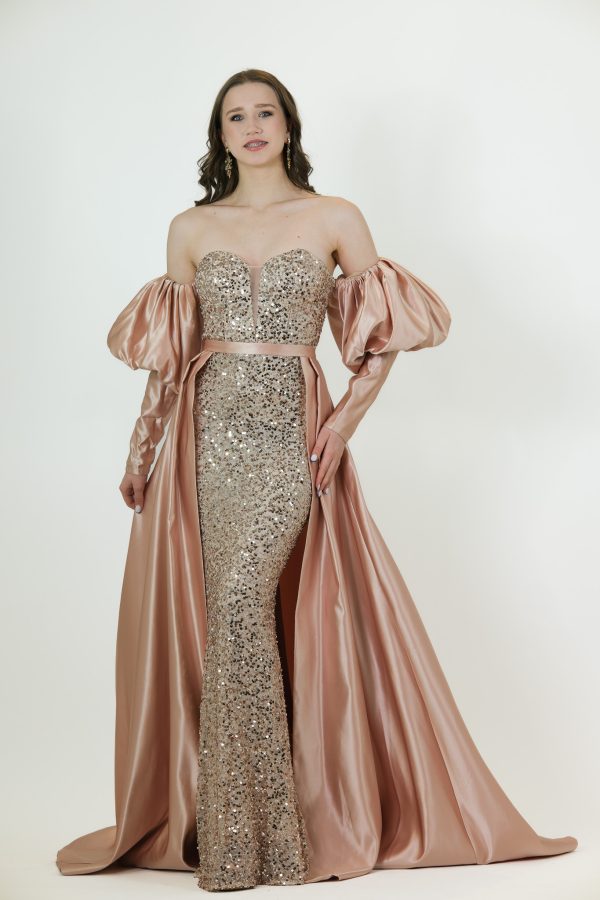 “Champagne sequin gown with rose-satin overskirt and off-shoulder puff sleeves.”