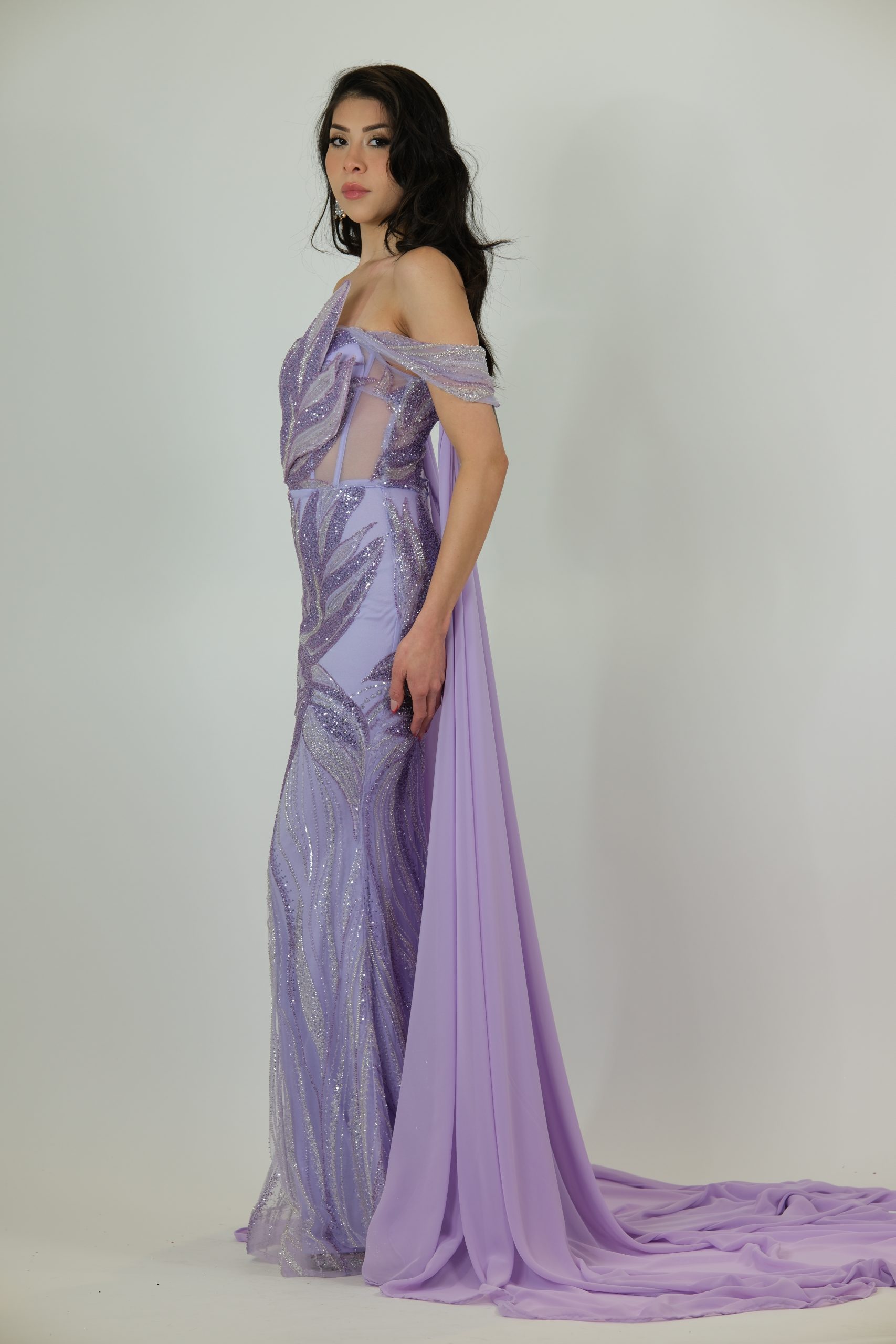 “Lilac sequin evening gown with off-shoulder applique detailing, sheer side panels, fitted skirt, and optional detachable chiffon cape.”