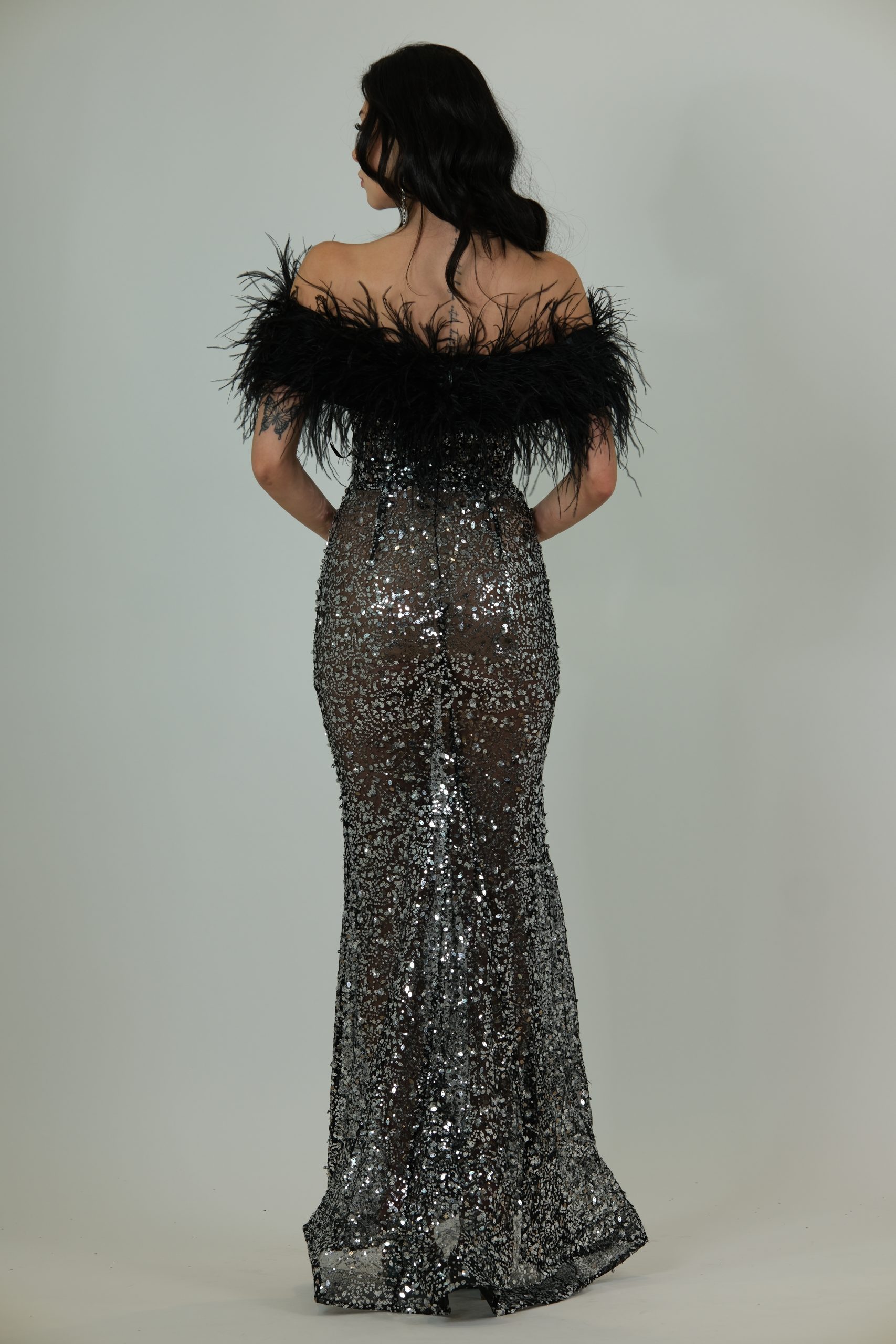 “Black and silver sequin gown with deep illusion neckline and dramatic black feather detailing.”