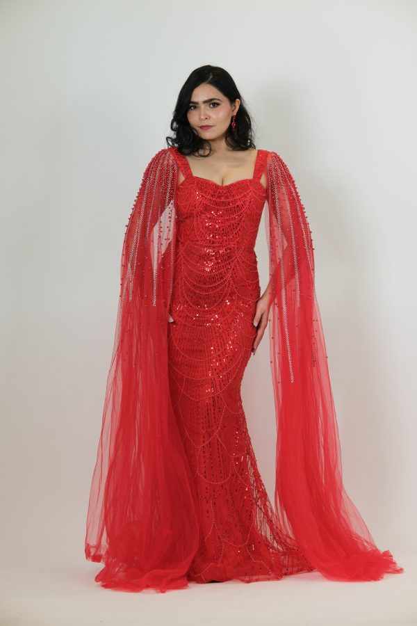 “Red fully beaded gown with scalloped sequin design and dramatic embellished tulle cape.”