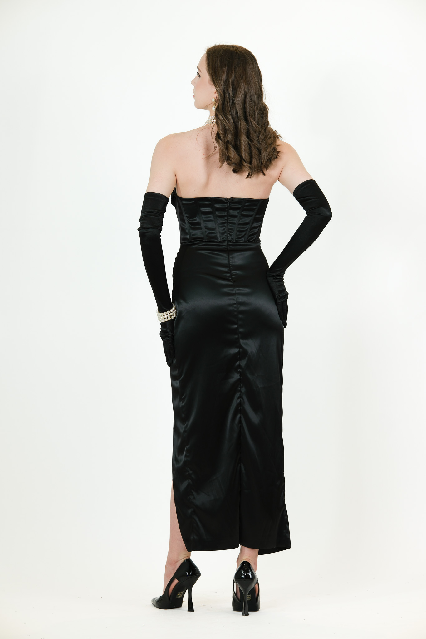 “Black satin strapless gown with corset bodice, ruched waist, and front slit.”