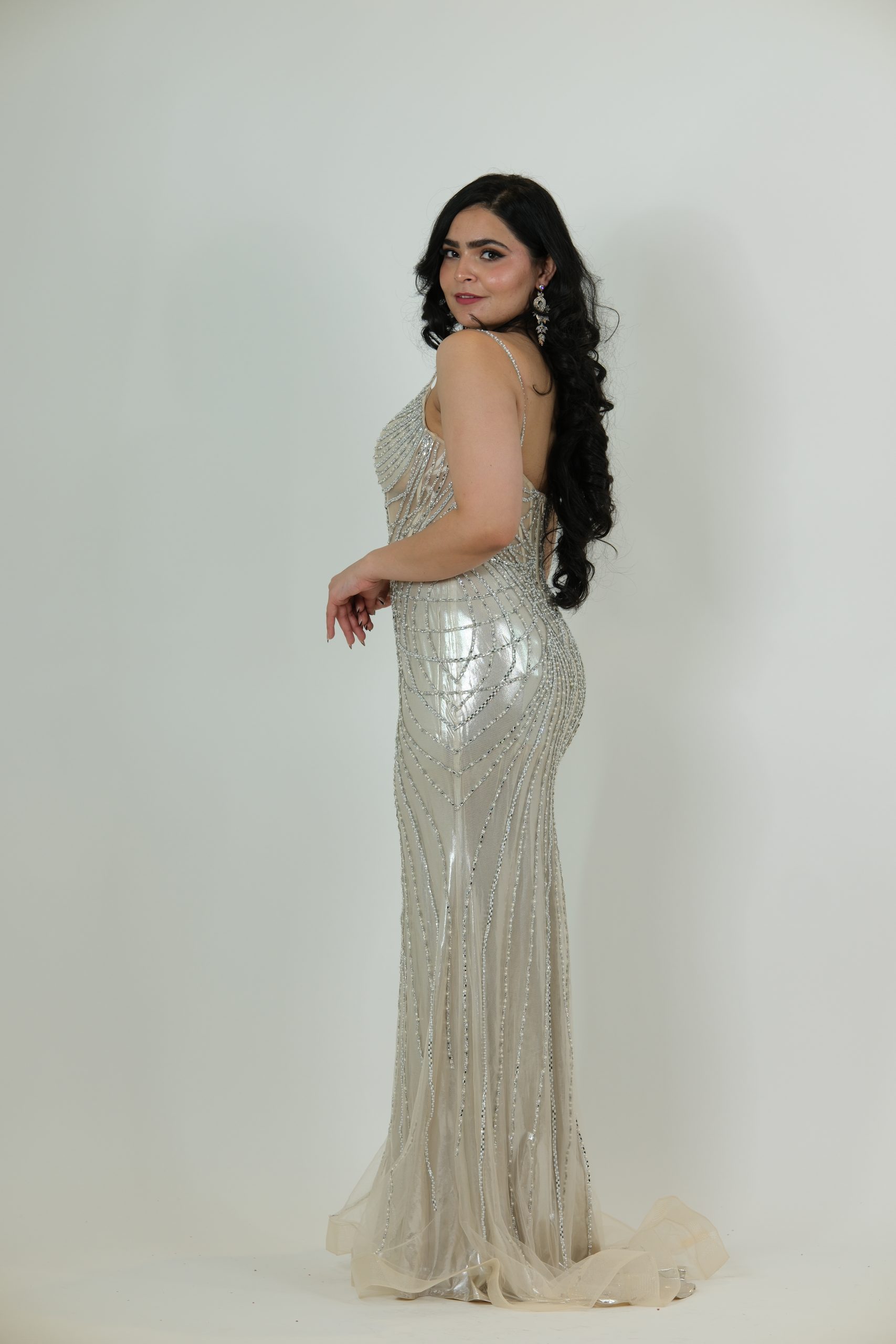 “Silver beaded mermaid gown with corset bodice, sheer detailing, and shimmering vertical embellishments.”